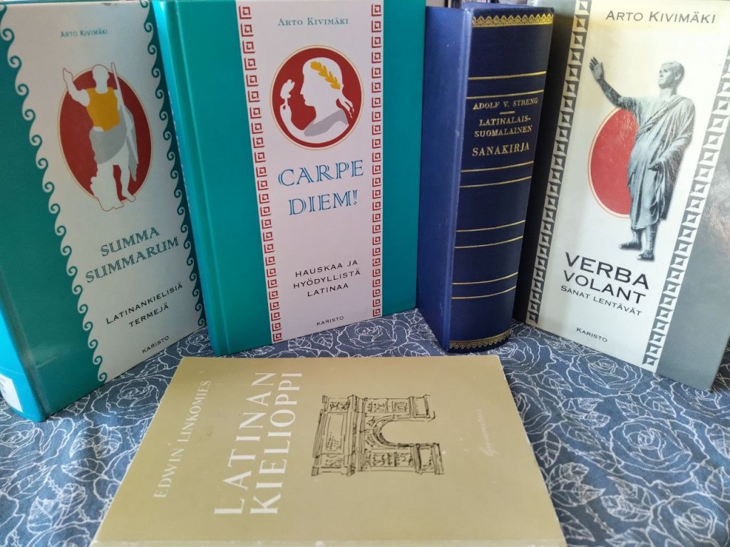 Asetelma kirjoja eli Arto Kivimäen Summa summarum, Arto Kivimäen Carpe diem, Arto Kivimäen Verba volant, Latinalais-suomalainen sanakirja ja Edwin Linkomiehen Latinan kielioppi