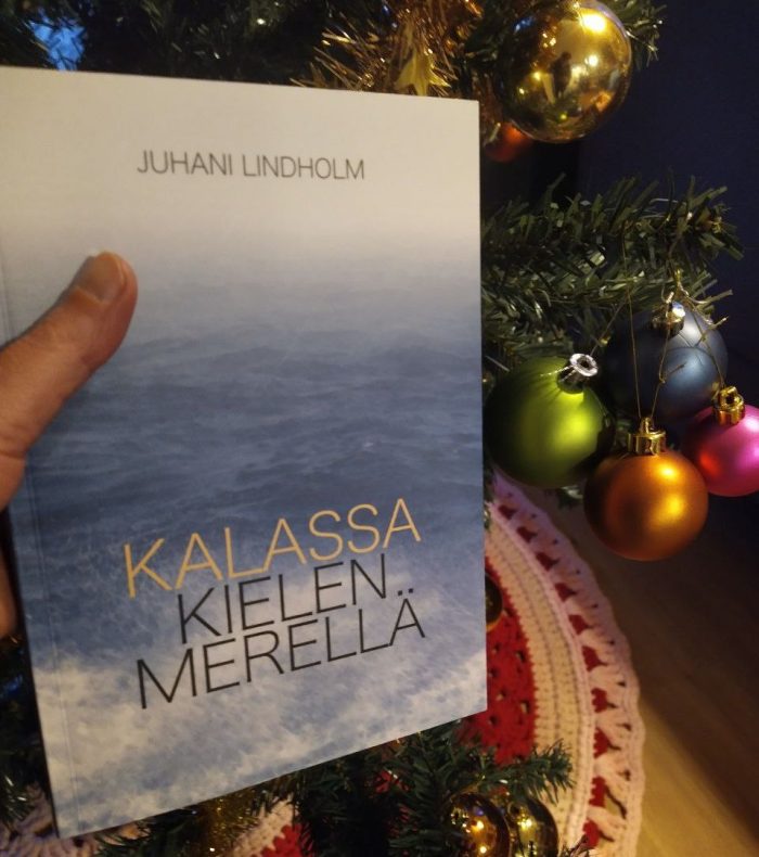 Kirjan Kalassa kielen merellä kansi kuvattuna värikkäiden joulupallojen edessä.