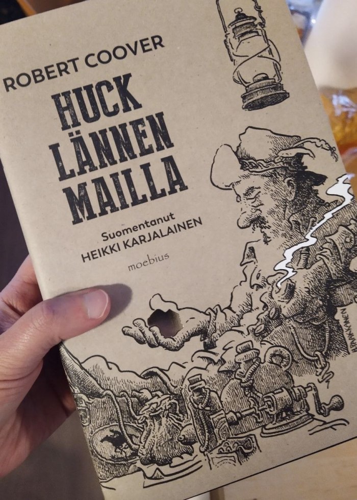 Valokuva kirjan kannesta. Taustaväri on rusehtavan värinen ja siinä lukee Robert Coover, Huck Lännen mailla, suomentanut Heikki Karjalainen, Moebius. Kuvaan on piirretty mustalla hattupäinen mies, joka istuu jalat pöydällä, piippu kädessä. Hänen päänsä yllä roikkuu lyhty ja edessä on pöydällä pulloja, nyssäköitä, työkaluja, sen sellaisia. Mies katselee toisella kädellään lepäävää kultakimpaletta. Kultakimpale on kullanväristä foliopainatusta ja piipusta nouseva savu vitivalkoista, kaikki muu on joko rusehtavaa taustaa tai mustaa piirrosviivaa. Kuvassa näkyy signeerauksena Paakkanen.