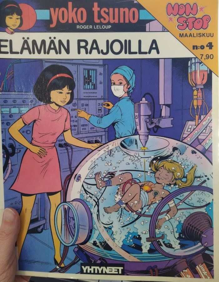 Valokuva sarjakuva-albumin kannesta. Kannessa lukee Yoko Tsuno Roger Leloup Elämän rajoilla, Non Stop, maaliskuu, nro 4. Kustantamon nimenä näkyy Yhtyneet ja hintana 7,90. Kuvassa on Yoko Tsuno pinkissä mekossa ihmettelemässä pallomaista tieteellis-teknistä kupua, jossa vedessä lilluu pikkutyttö. Tyttöön kulkee johtoja ja on kiinnitetty elektrodi rintaan. Yläpuolelta hänen rintaansa ammutaan kuvun ulkopuolelta sisäpuolelle lasersädettä jollakin vehkeellä. Pallossa on poreita. Tyttö näyttää levolliselta siellä. Taustalla on leikkaussaliasuinen nainen seinän kokoisen koneen ääressä painelemassa nappeja ja vääntelemässä vipstaakeja, mutta hänkin on kääntynyt katselemaan lasta. Taustalla on eräänlaiset tippapullot, josta valuu pinkkiä ja oranssia nestettä jonnekin letkuihin kuin ketsuppia ja sinappia.